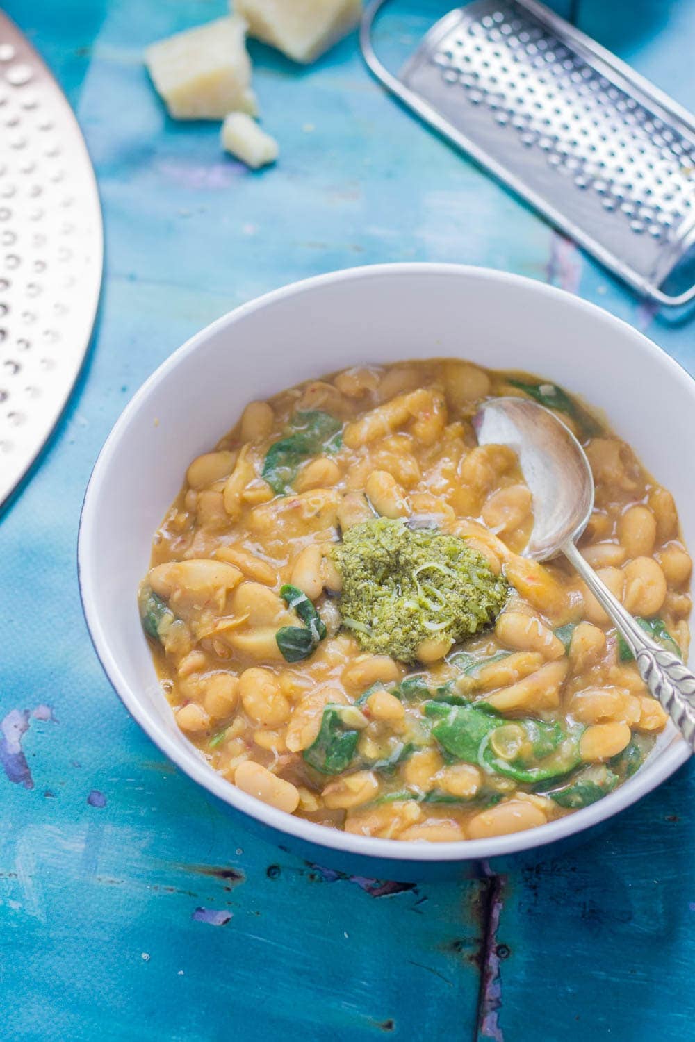 Beans are cooked with bacon, garlic & chicken stock to make this tasty white bean stew. Topped with a homemade pesto for a comforting winter dinner. 