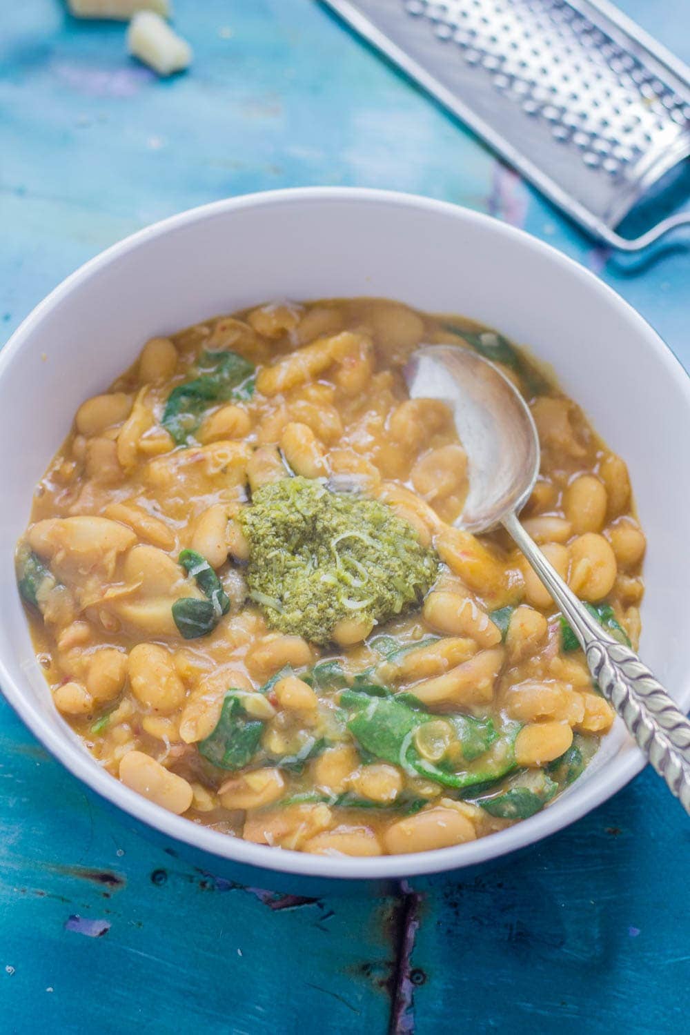 Beans are cooked with bacon, garlic & chicken stock to make this tasty white bean stew. Topped with a homemade pesto for a comforting winter dinner. 