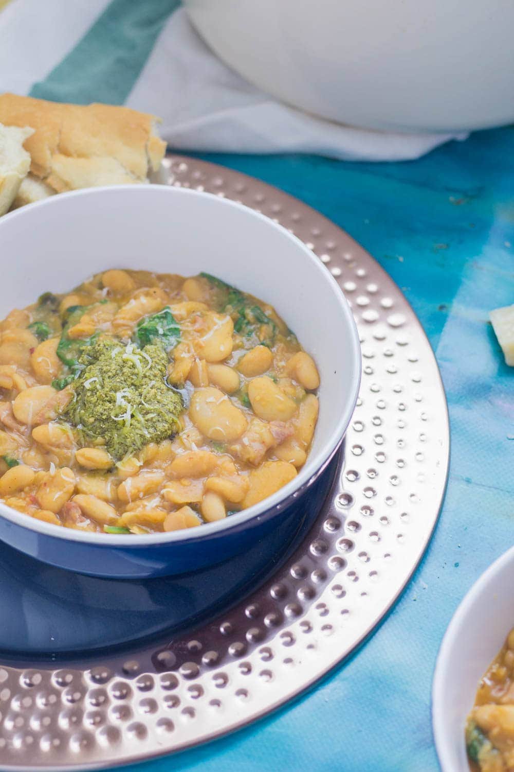 Beans are cooked with bacon, garlic & chicken stock to make this tasty white bean stew. Topped with a homemade pesto for a comforting winter dinner.