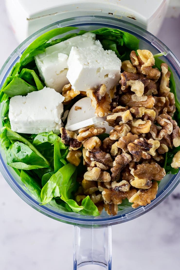 Overhead shot of blender with ingredients for spinach pesto with feta