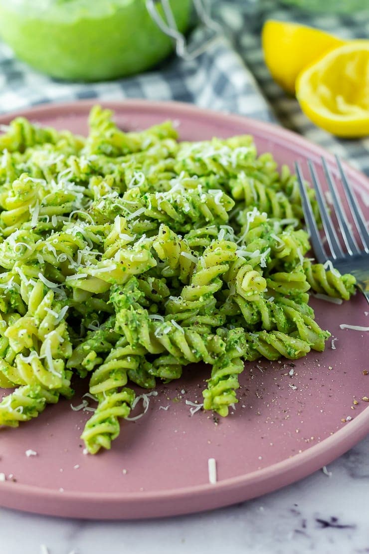 Pasta with spinach pesto on a pink plate on a marble background