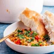 Side on shot of menemen with bread in a white bowl on a blue background