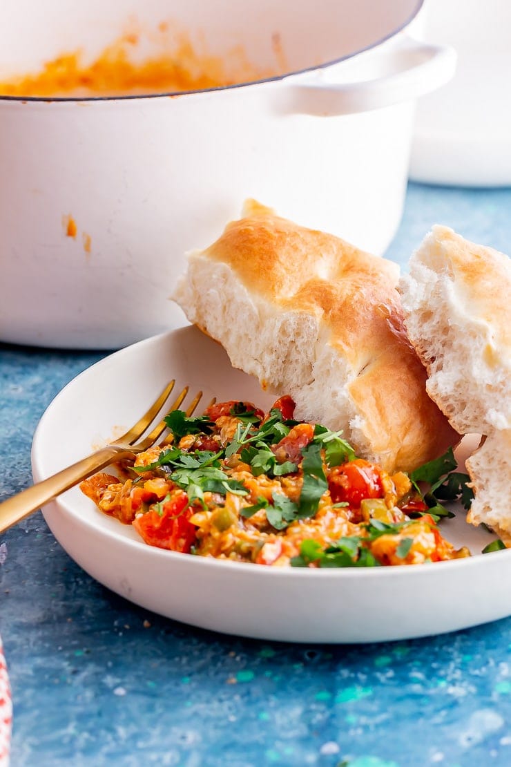 Side on shot of menemen with bread in a white bowl on a blue background