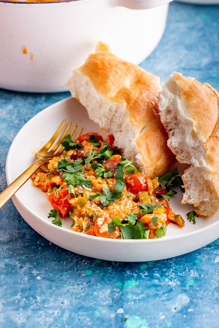 White bowl of Turkish scrambled eggs with a gold fork on a blue background