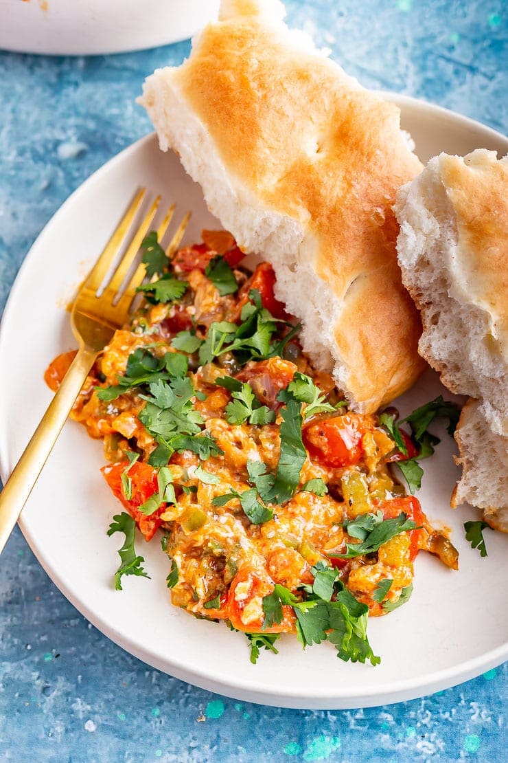 White bowl of menemen with bread and a gold fork