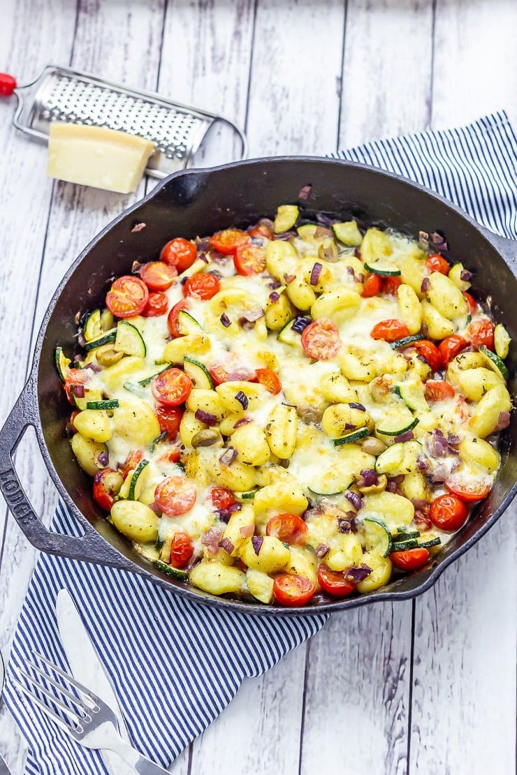 Summer gnocchi skillet on a striped cloth and white wooden background