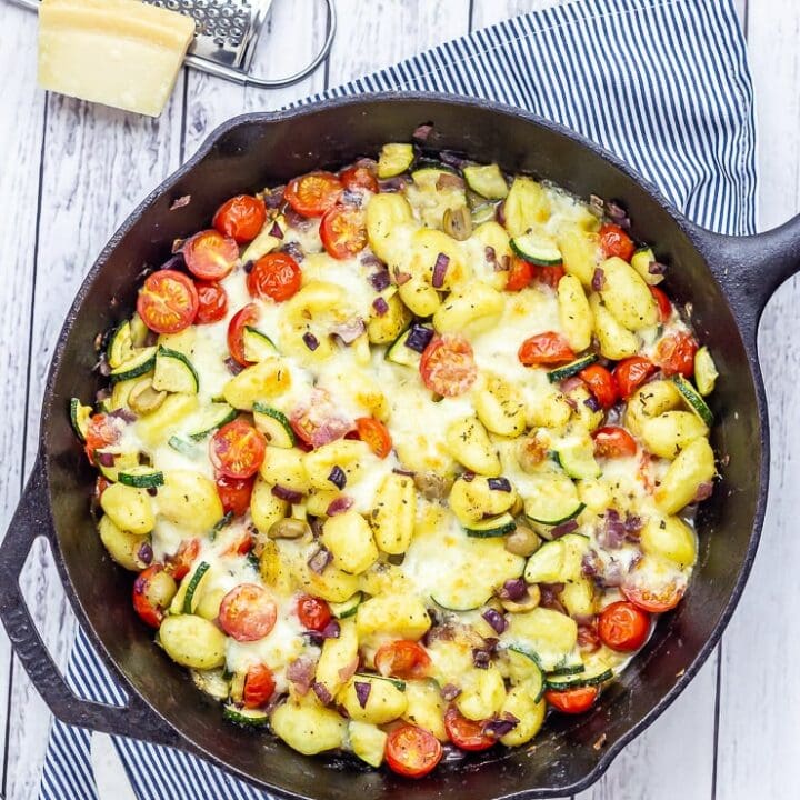 Overhead shot of summer gnocchi skillet on a white wooden background