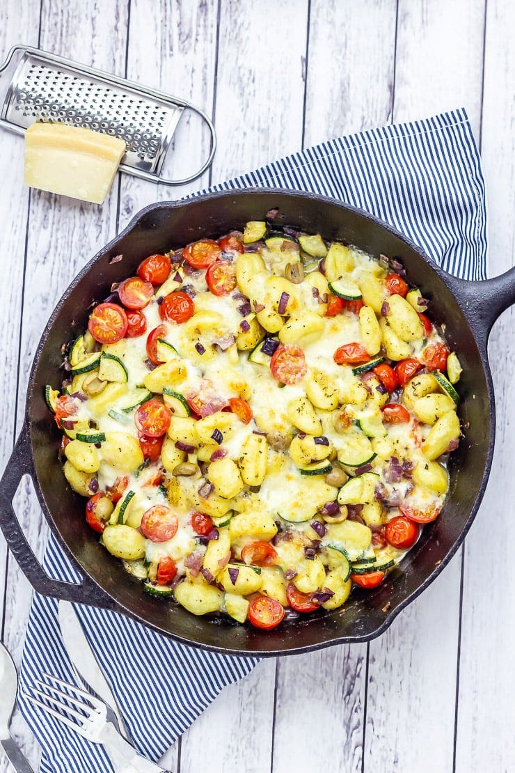 Overhead shot of summer gnocchi skillet on a white wooden background