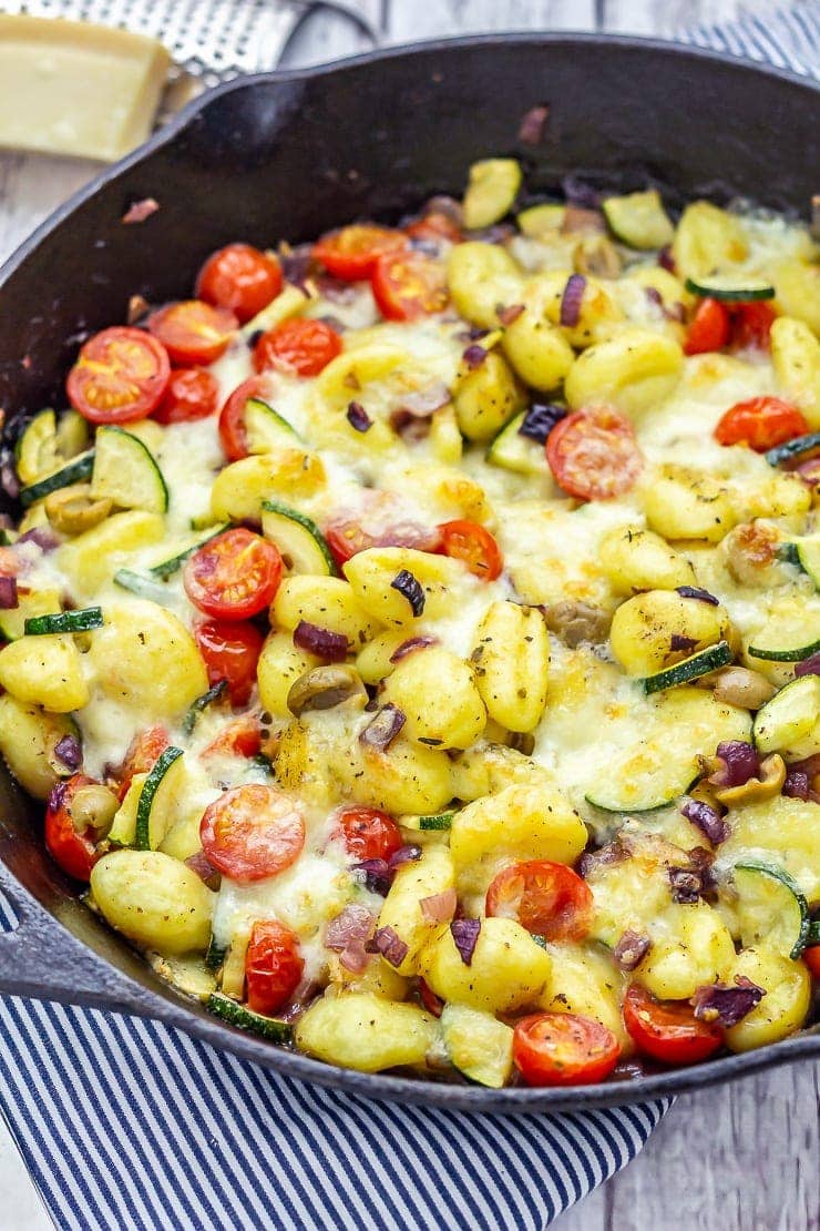 Summer gnocchi skillet on a striped cloth with parmesan in the background