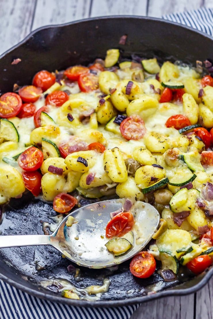 Summer gnocchi skillet with a portion taken and a metal spoon