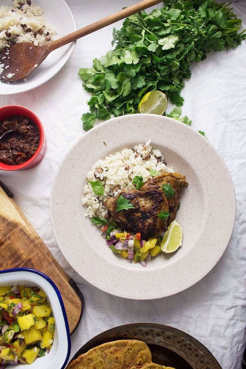 This jerk chicken is sweet and spicy, it tastes amazing served with a mango salsa and turmeric roti. Rice & peas is the perfect base for all this deliciousness!
