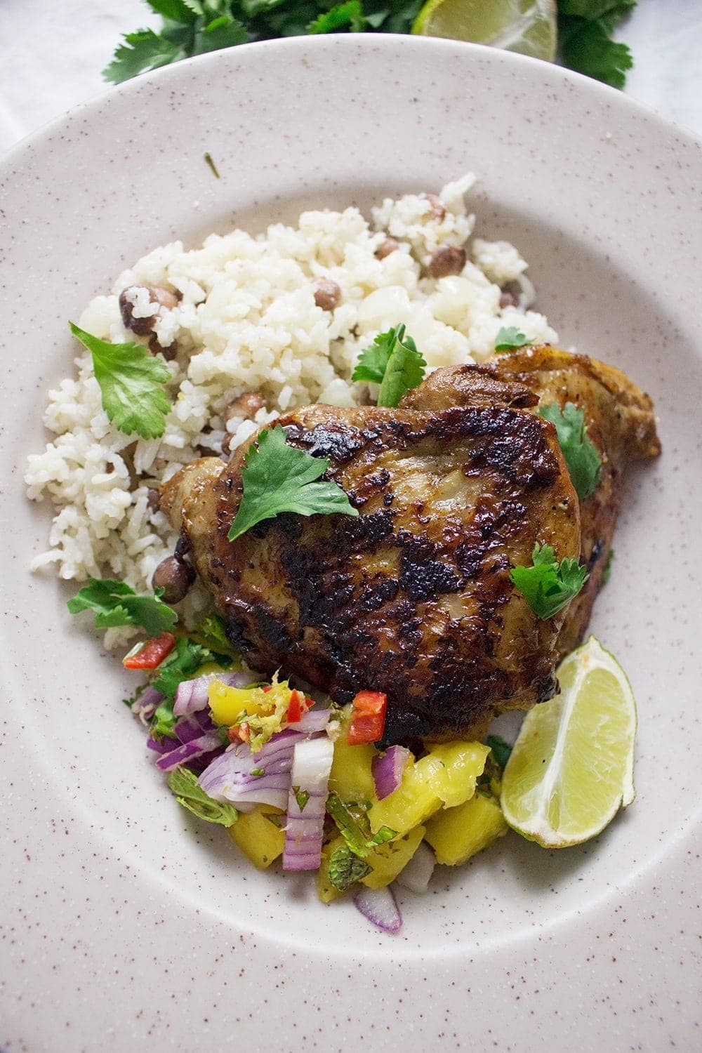 This jerk chicken is sweet and spicy, it tastes amazing served with a mango salsa and turmeric roti. Rice & peas is the perfect base for all this deliciousness!