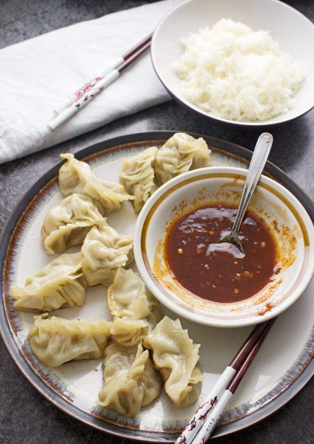 These pork potstickers with a chilli dipping sauce are filling, tasty, & easier than you think! Use premade dumpling wrappers to be ready in under an hour.