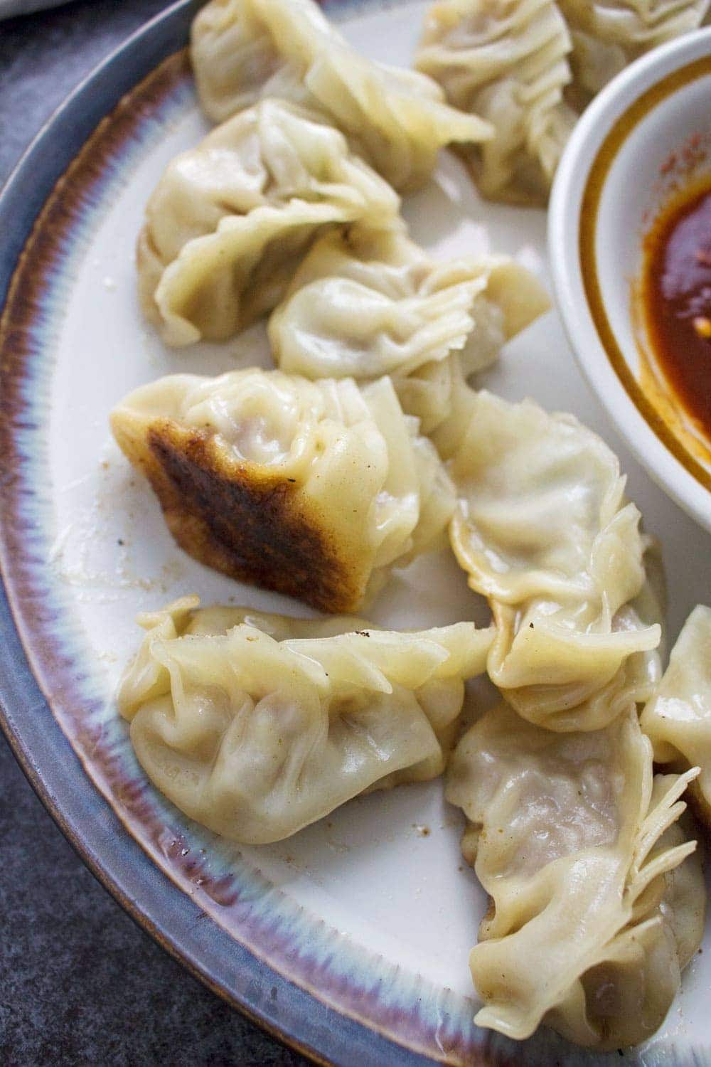 These pork potstickers with a chilli dipping sauce are filling, tasty, & easier than you think! Use premade dumpling wrappers to be ready in under an hour.