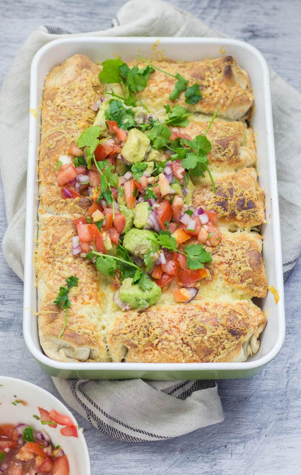 Baking dish of beef enchiladas topped with salsa