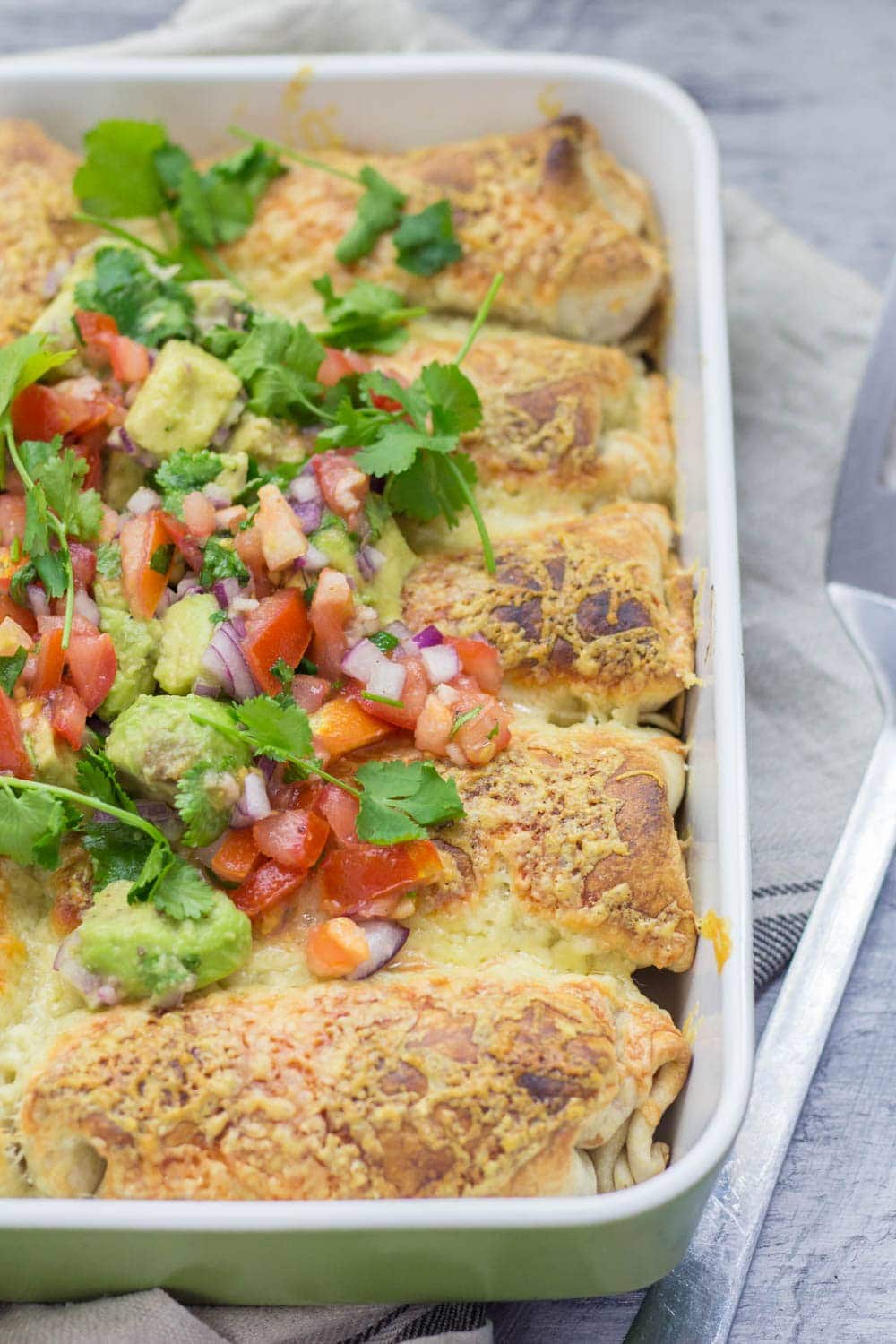 Beef enchiladas topped with avocado and tomato