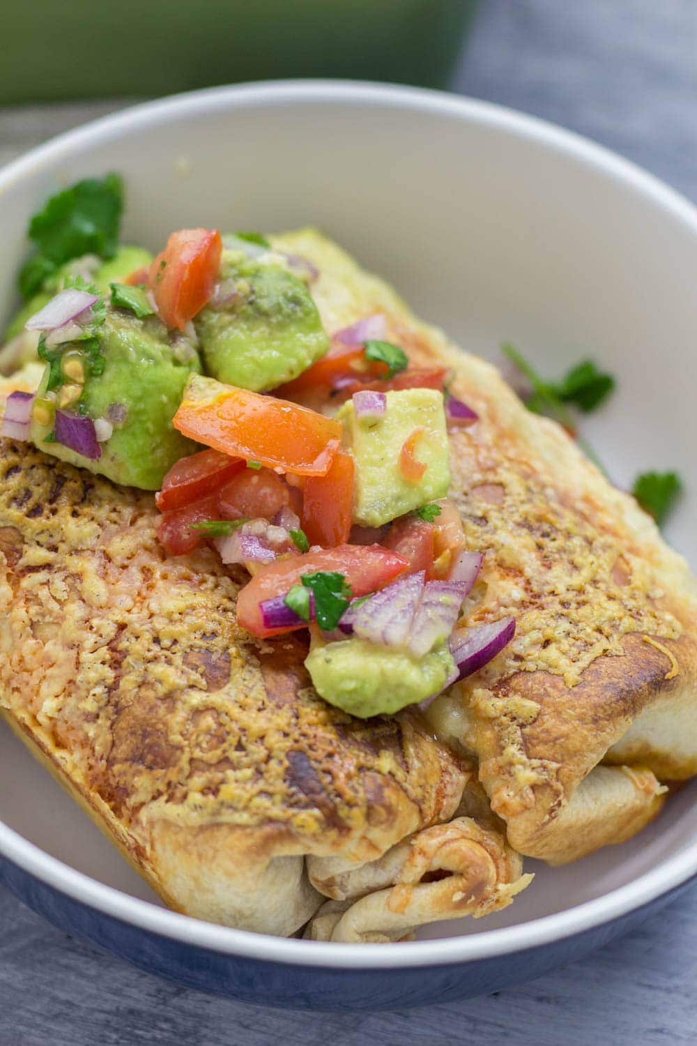 Bowl of beef enchiladas topped with avocado