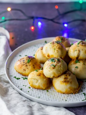 Side on shot of pesto mozzarella stuffed dough balls on a grey plate with lights in the background