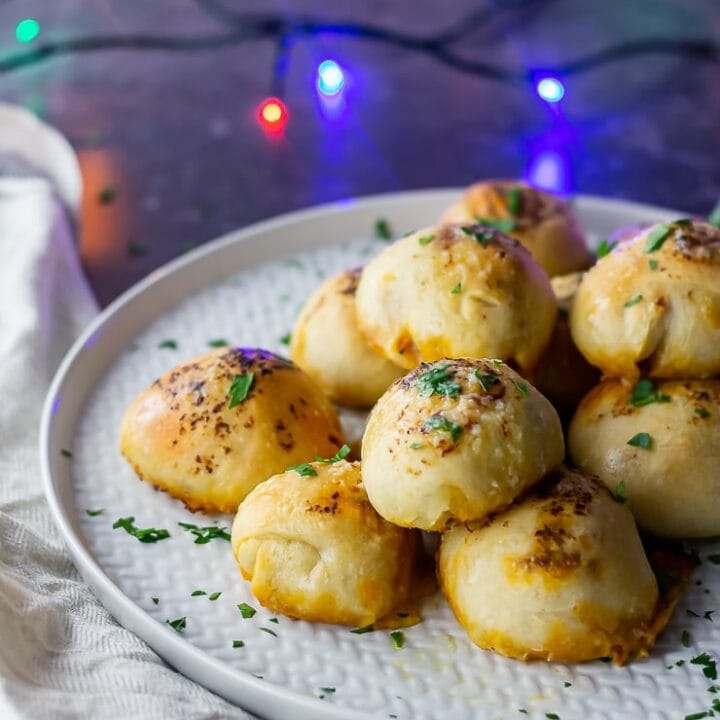 Side on shot of pesto mozzarella stuffed dough balls on a grey plate with lights in the background