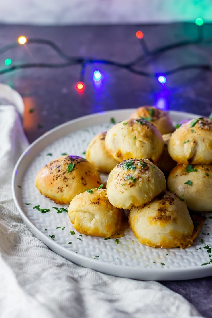 Side on shot of pesto mozzarella stuffed dough balls on a grey plate with lights in the background