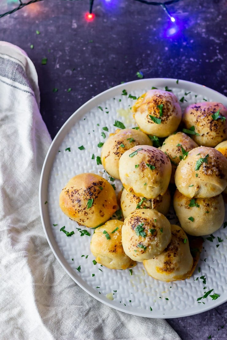 Overhead shot of pesto mozzarella stuffed dough balls on a grey plate over a dark background