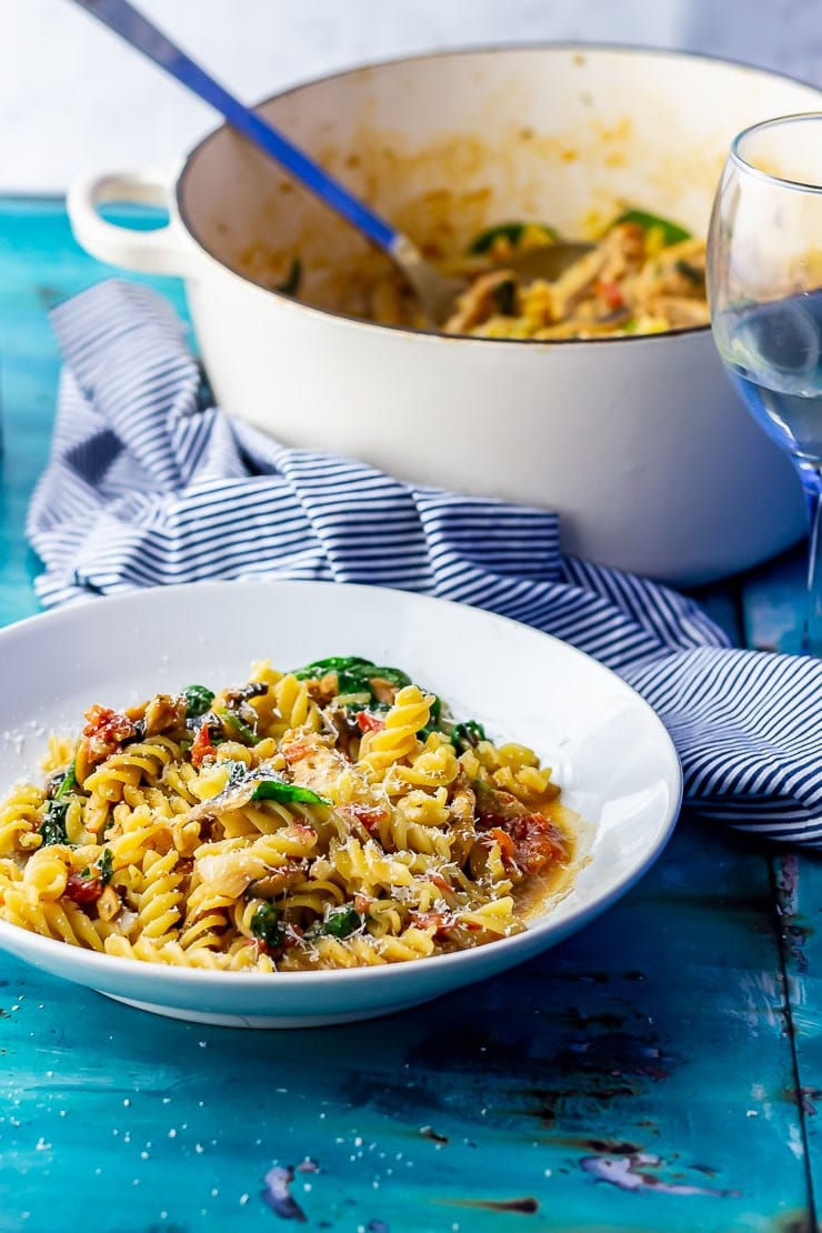 Side on shot of one pot pasta in a white bowl on a blue background