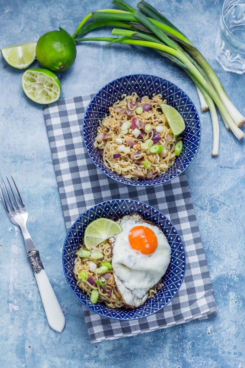 Overhead shot of two bowls of soy peanut noodles on a checked cloth