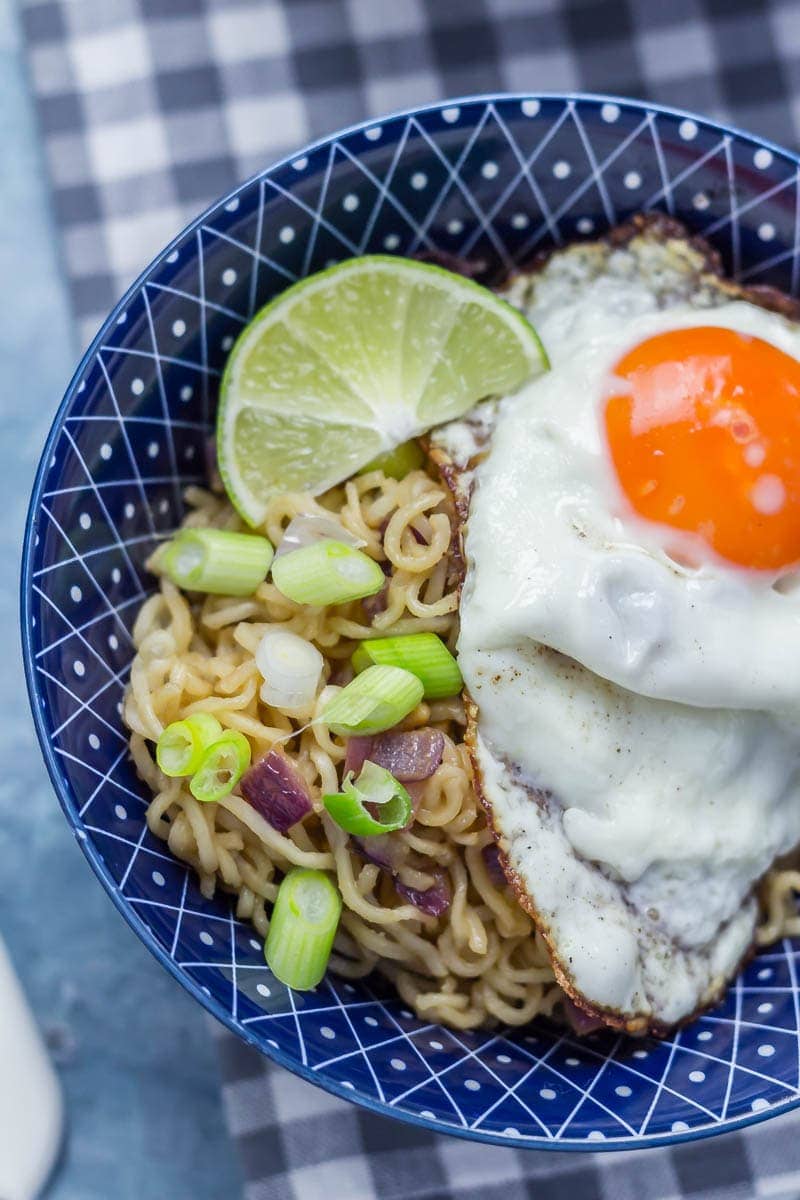 Close up of soy peanut noodles with a fried egg and lime