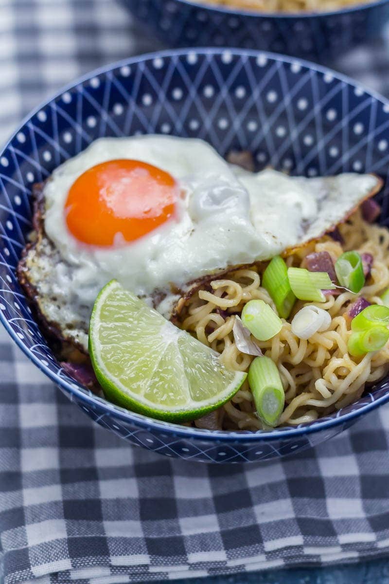 Egg and lime on a soy peanut noodles in a blue bowl