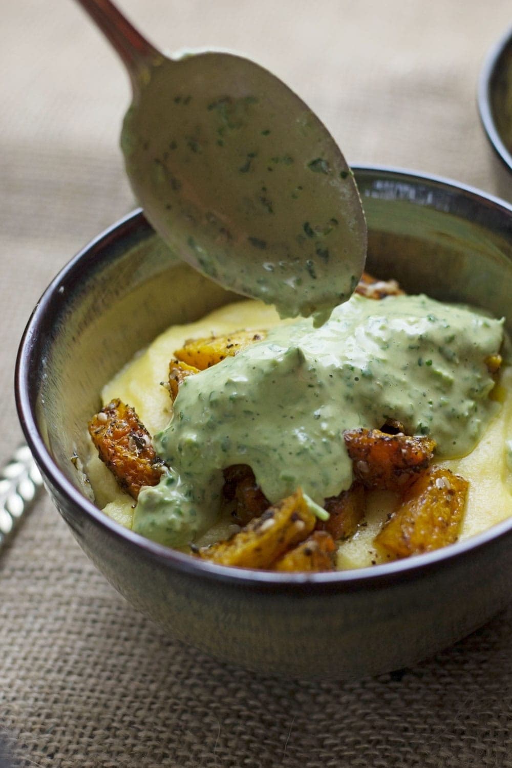 This roasted butternut squash is coated with za'atar before going in the oven then served over creamy goat's cheese polenta and topped with a herby tahini sauce.