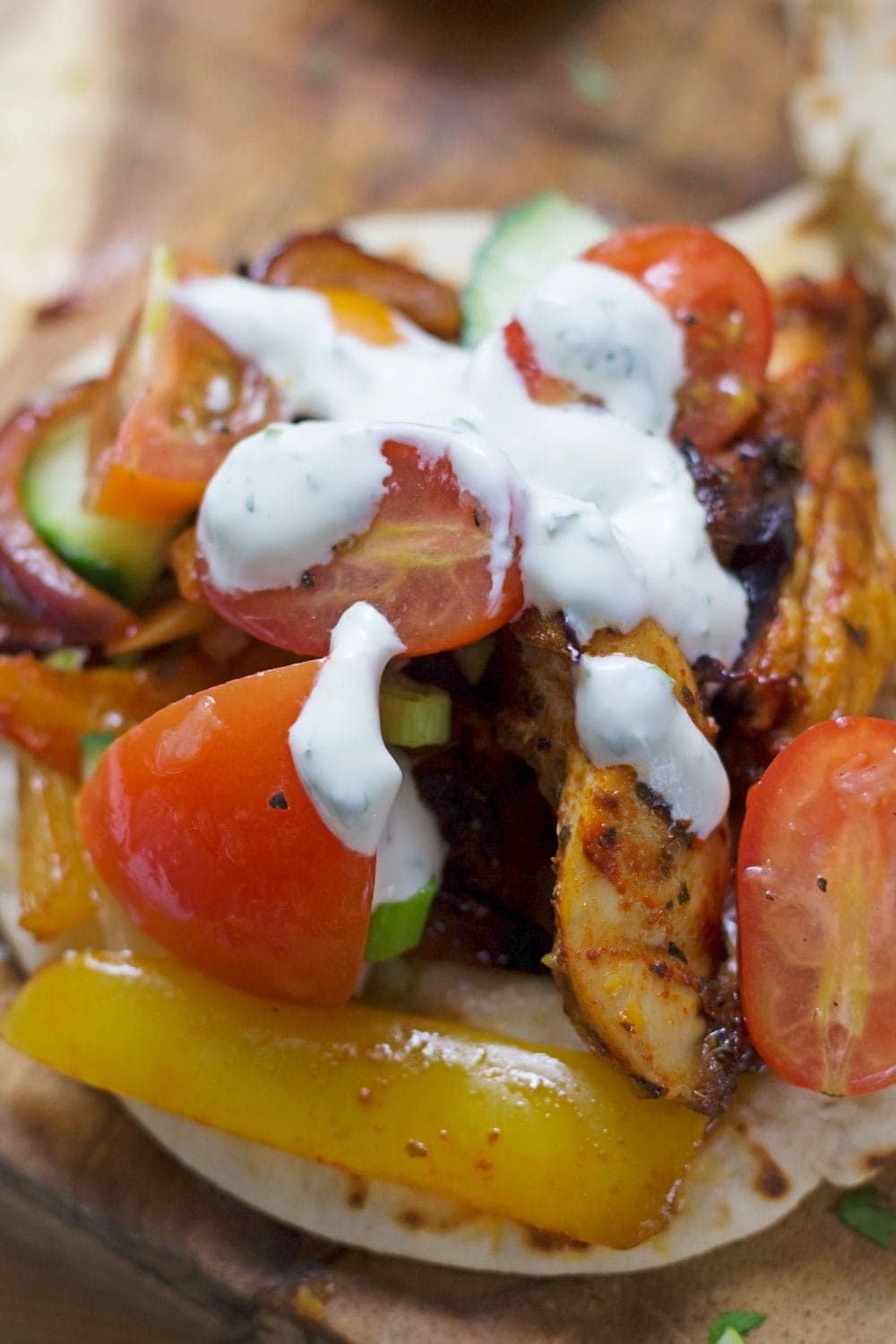 This sheet pan Greek chicken is served in a flatbread with garlicky marinated tomatoes and an incredible herby sour cream sauce!