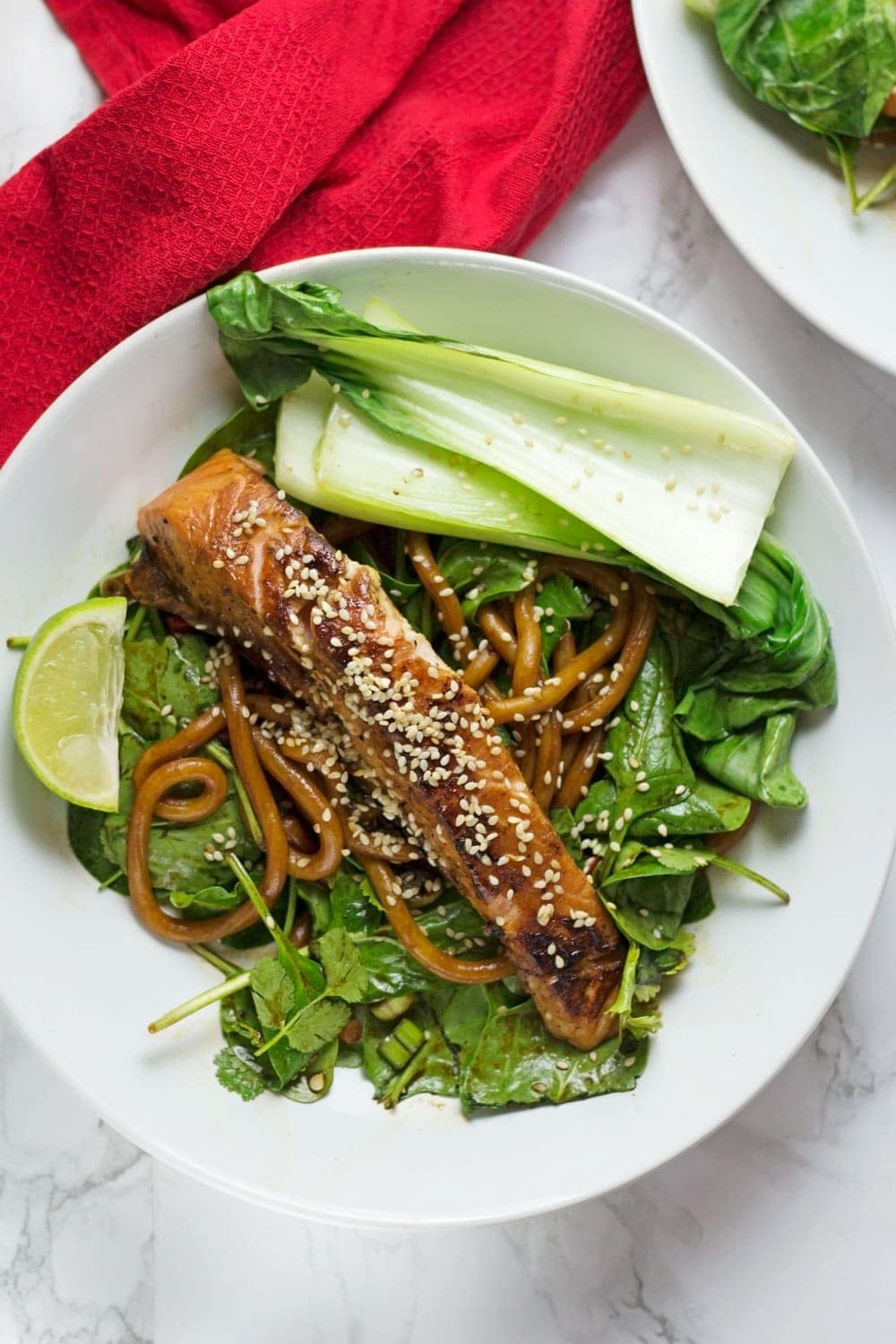 Teriyaki salmon on spinach in a white bowl