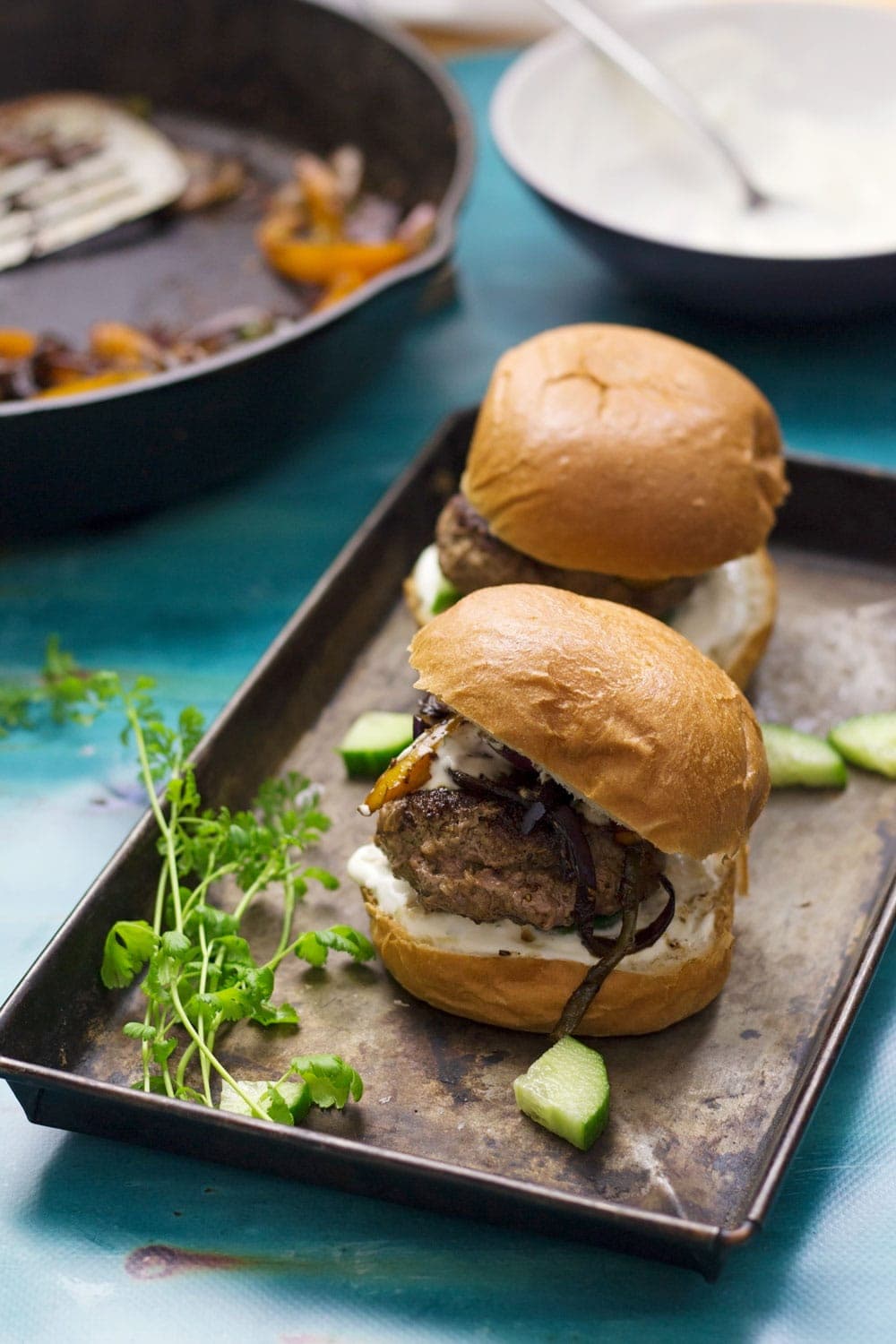 These Greek lamb burgers are served in a brioche bun. Topped with caramelised pepper and onion, refreshing cucumber and a drizzle of garlicky Greek yoghurt!