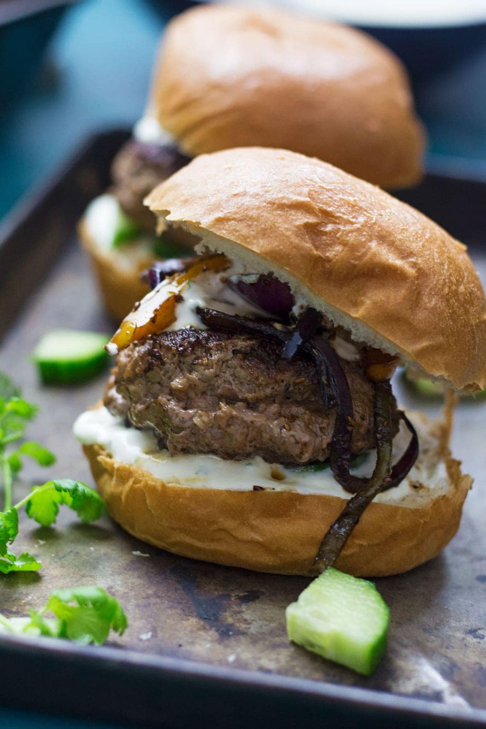 These Greek lamb burgers are served in a brioche bun. Topped with caramelised pepper and onion, refreshing cucumber and a drizzle of garlicky Greek yoghurt!