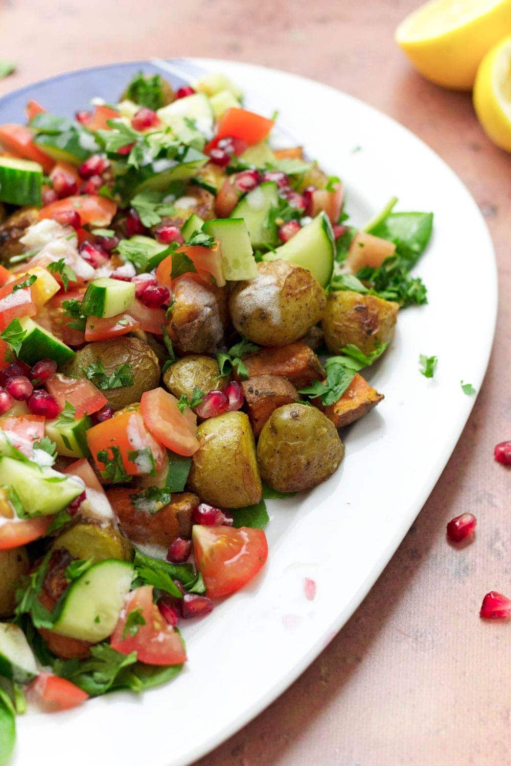 One edge of potato salad platter with pomegranate and lemon