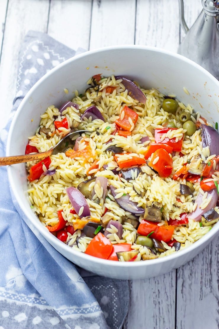 Summer orzo salad in a bowl on a white wooden background