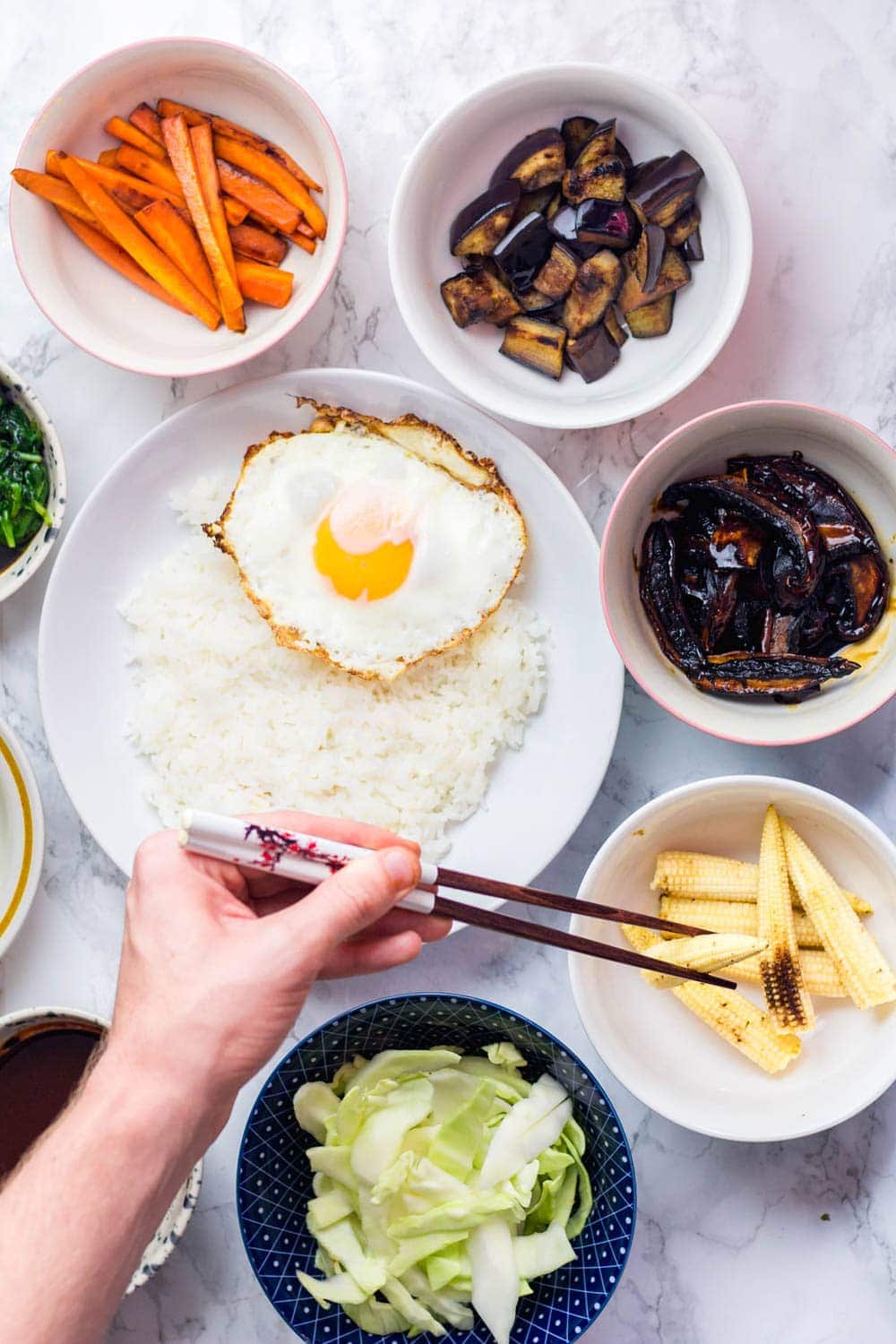 Overhead shot of hand holding chopsticks with bibimbap