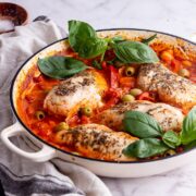 White skillet on a marble background with Italian chicken and basil