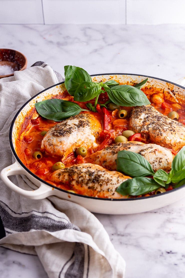 White skillet on a marble background with Italian chicken and basil