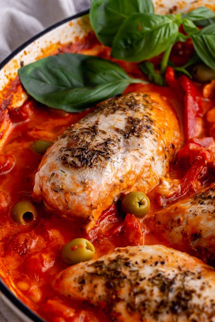 Close up of chicken in a creamy Italian sauce with olives and basil