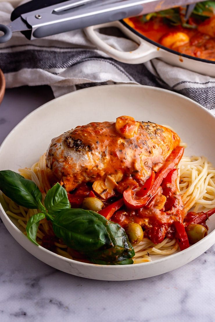 White bowl of chicken and spaghetti on a marble background