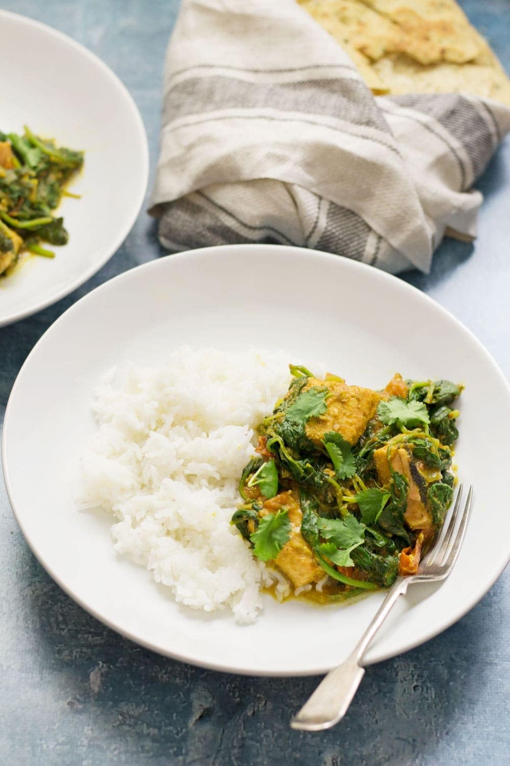 White bowl of salmon curry on a blue background