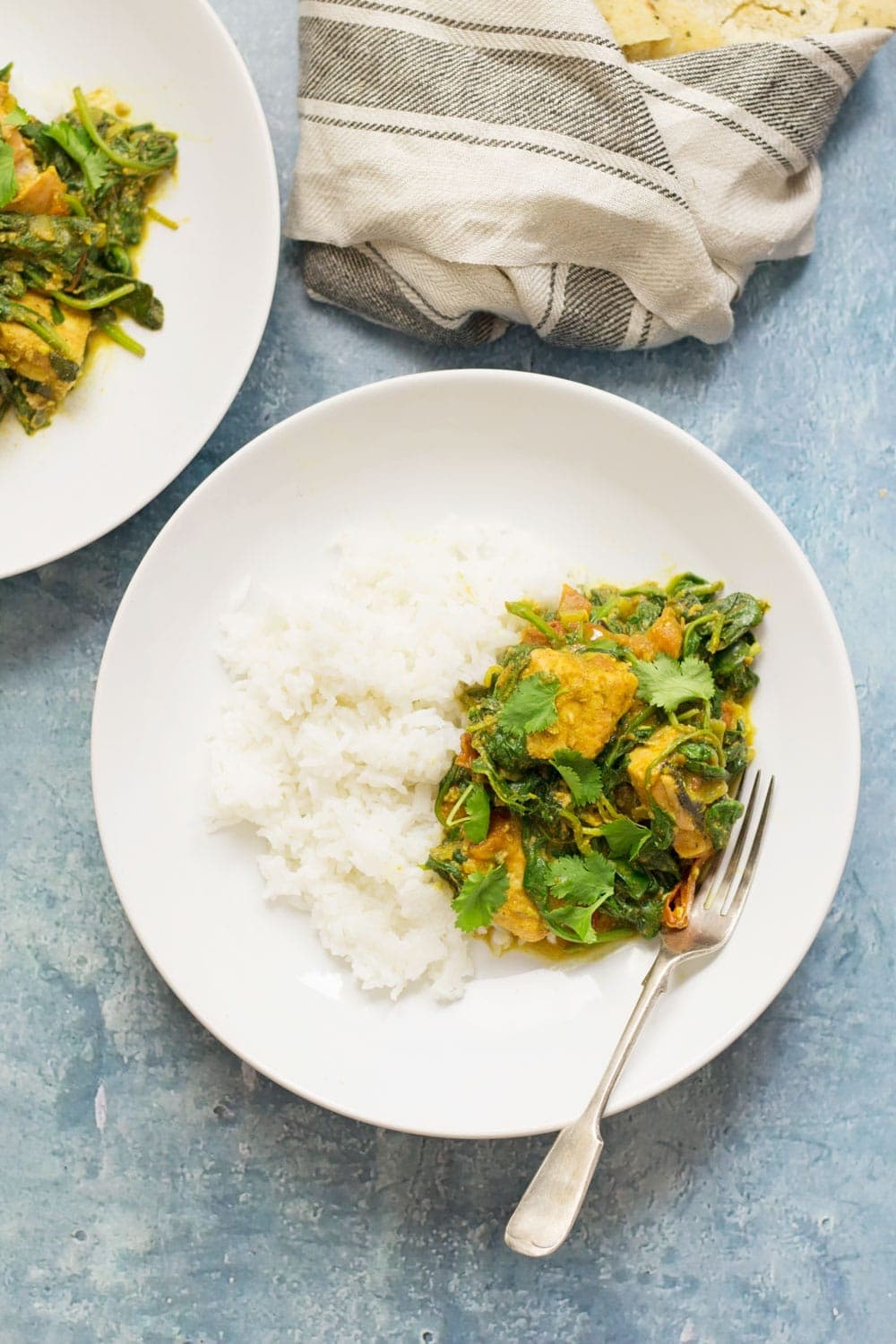 Overhead shot of white bowls of salmon curry on a blue background