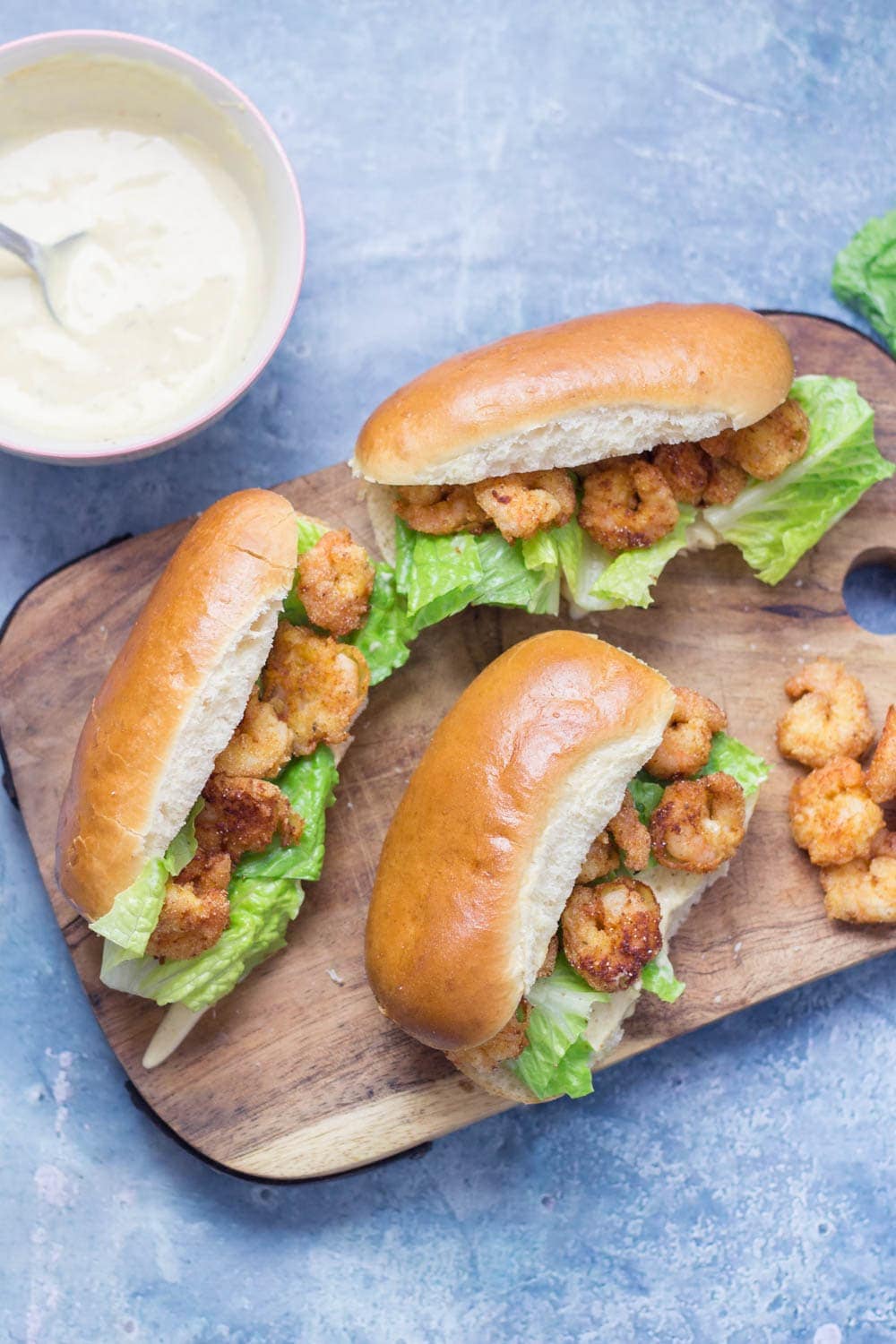 Prawn po' boys are made up of crispy prawns nestled into a bread roll with crunchy lettuce & tangy Cajun sauce. Bring a taste of New Orleans to your home! #sandwich #seafood #poboy #cajunfood #recipe