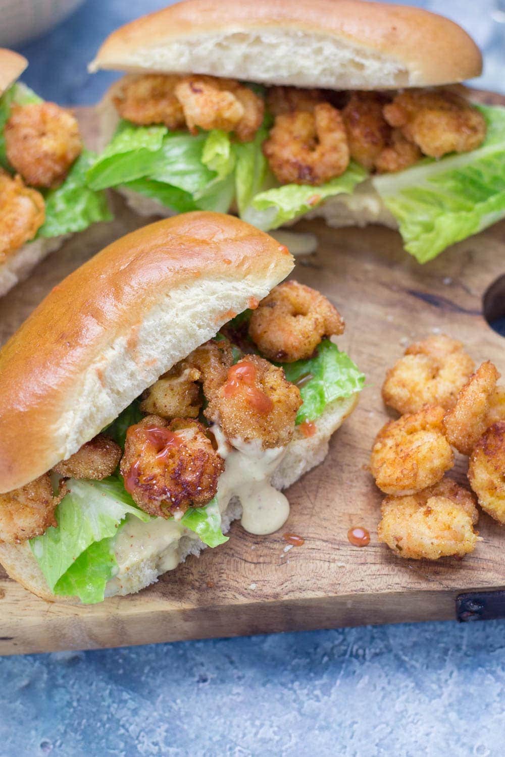 Prawn po' boys are made up of crispy prawns nestled into a bread roll with crunchy lettuce & tangy Cajun sauce. Bring a taste of New Orleans to your home! #sandwich #seafood #poboy #cajunfood #recipe