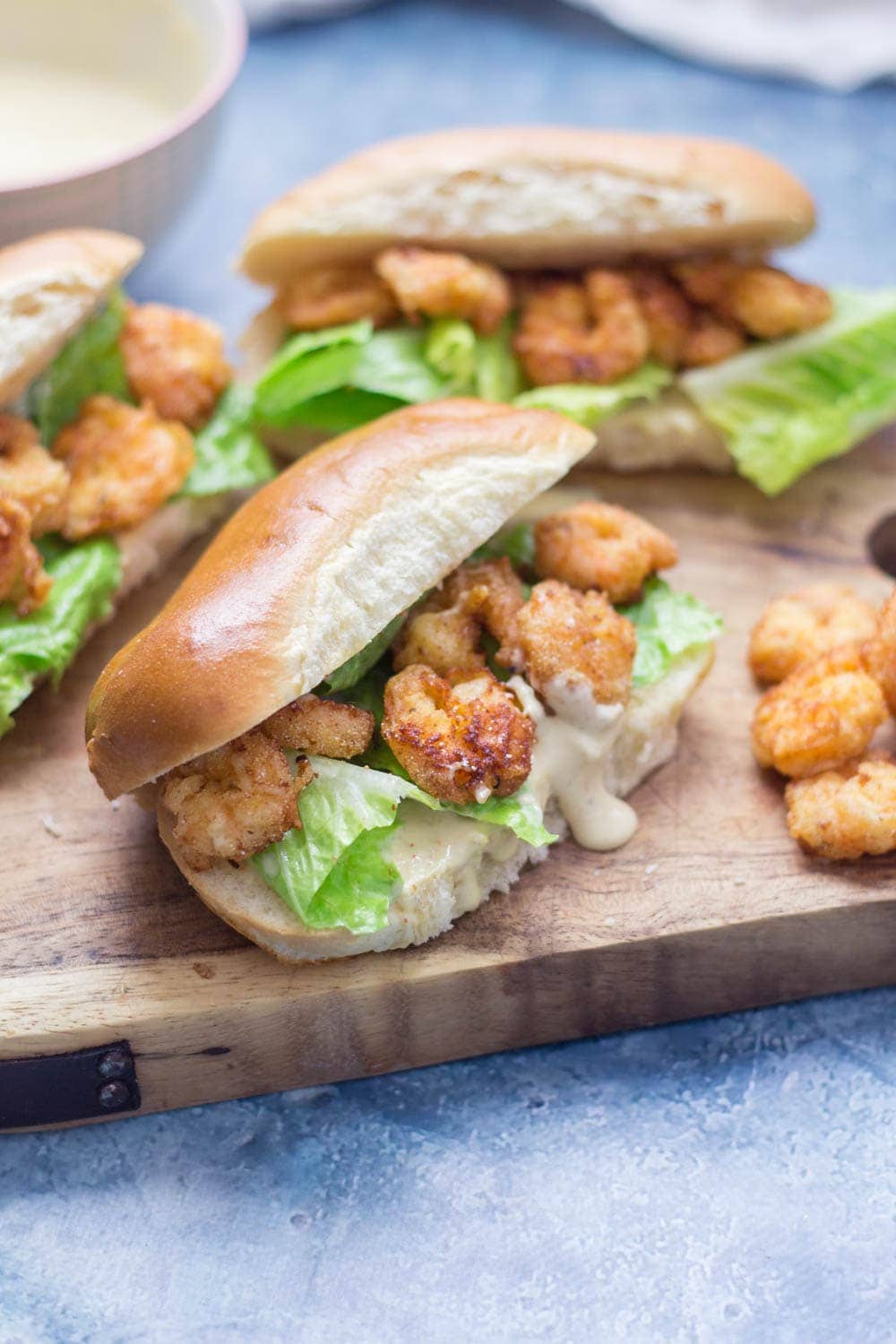 Prawn po' boys are made up of crispy prawns nestled into a bread roll with crunchy lettuce & tangy Cajun sauce. Bring a taste of New Orleans to your home! #sandwich #seafood #poboy #cajunfood #recipe