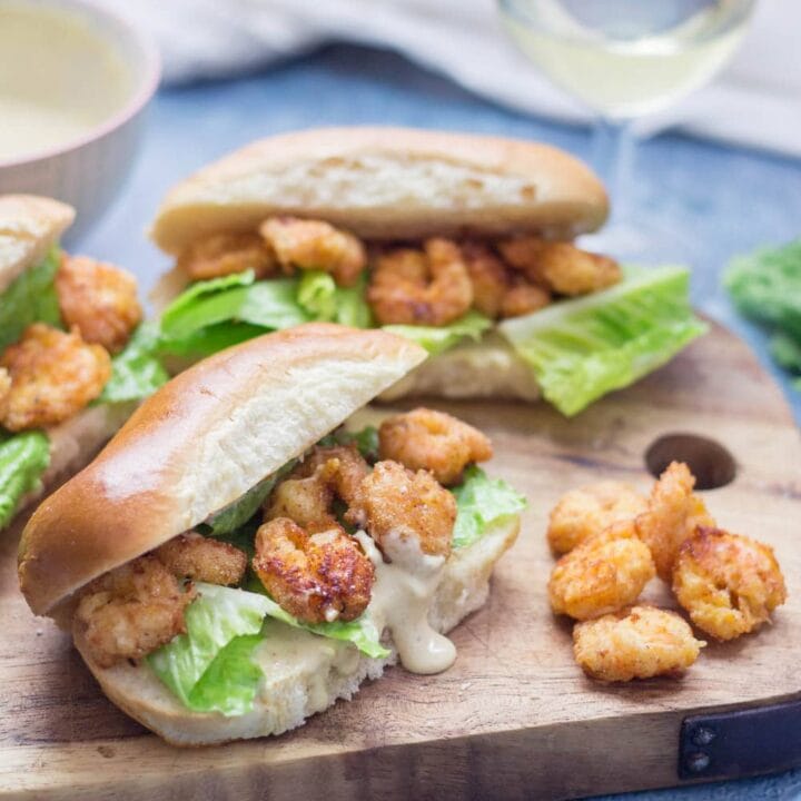 Prawn po' boys are made up of crispy prawns nestled into a bread roll with crunchy lettuce & tangy Cajun sauce. Bring a taste of New Orleans to your home! #sandwich #seafood #poboy #cajunfood #recipe