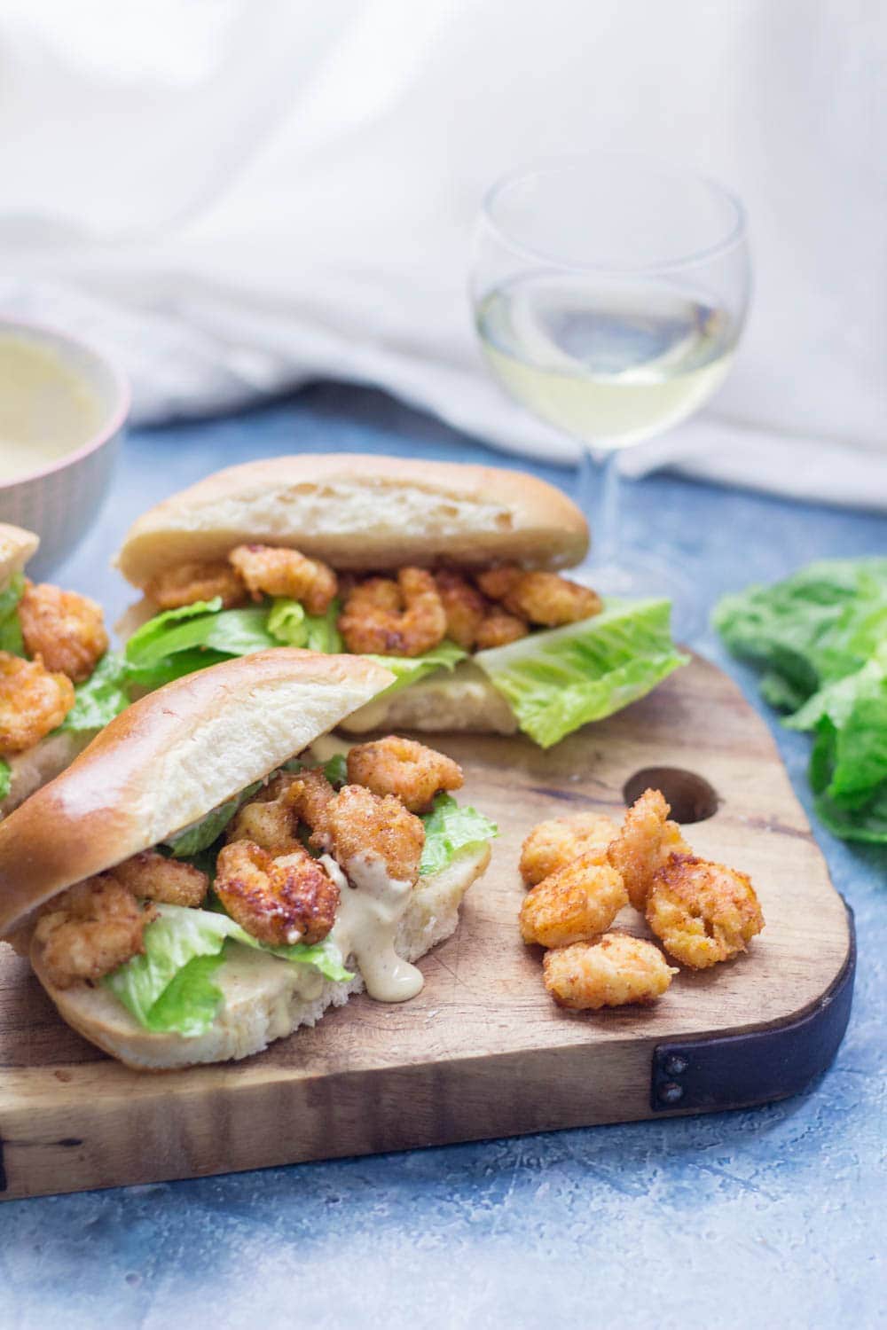 Prawn po' boys are made up of crispy prawns nestled into a bread roll with crunchy lettuce & tangy Cajun sauce. Bring a taste of New Orleans to your home! #sandwich #seafood #poboy #cajunfood #recipe