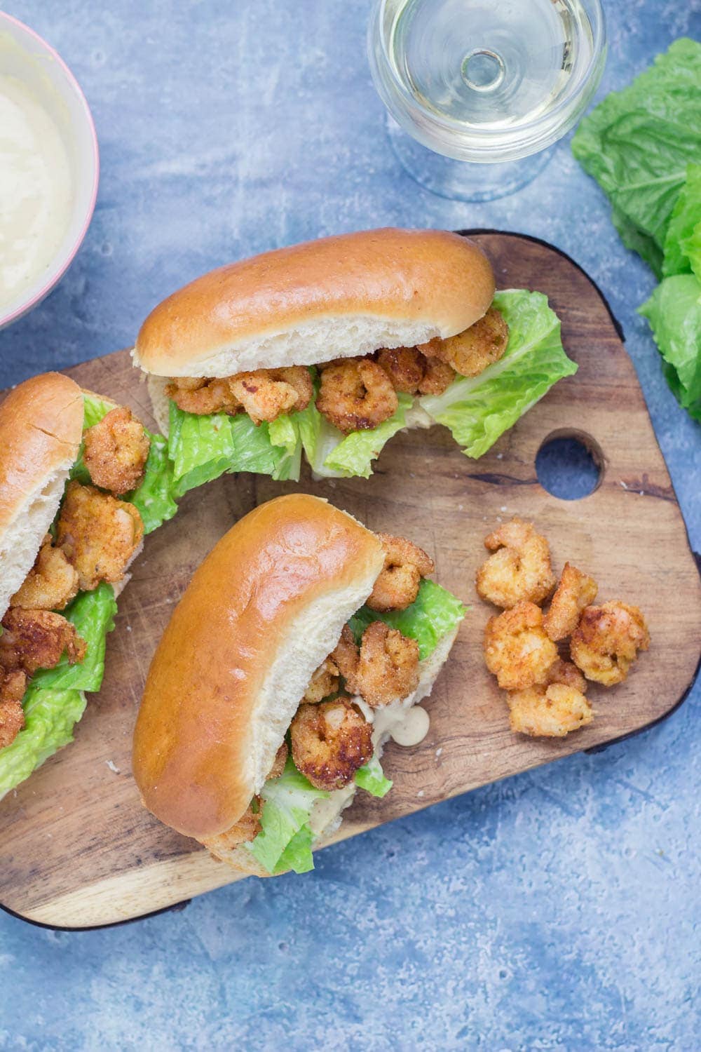 Prawn po' boys are made up of crispy prawns nestled into a bread roll with crunchy lettuce & tangy Cajun sauce. Bring a taste of New Orleans to your home! #sandwich #seafood #poboy #cajunfood #recipe
