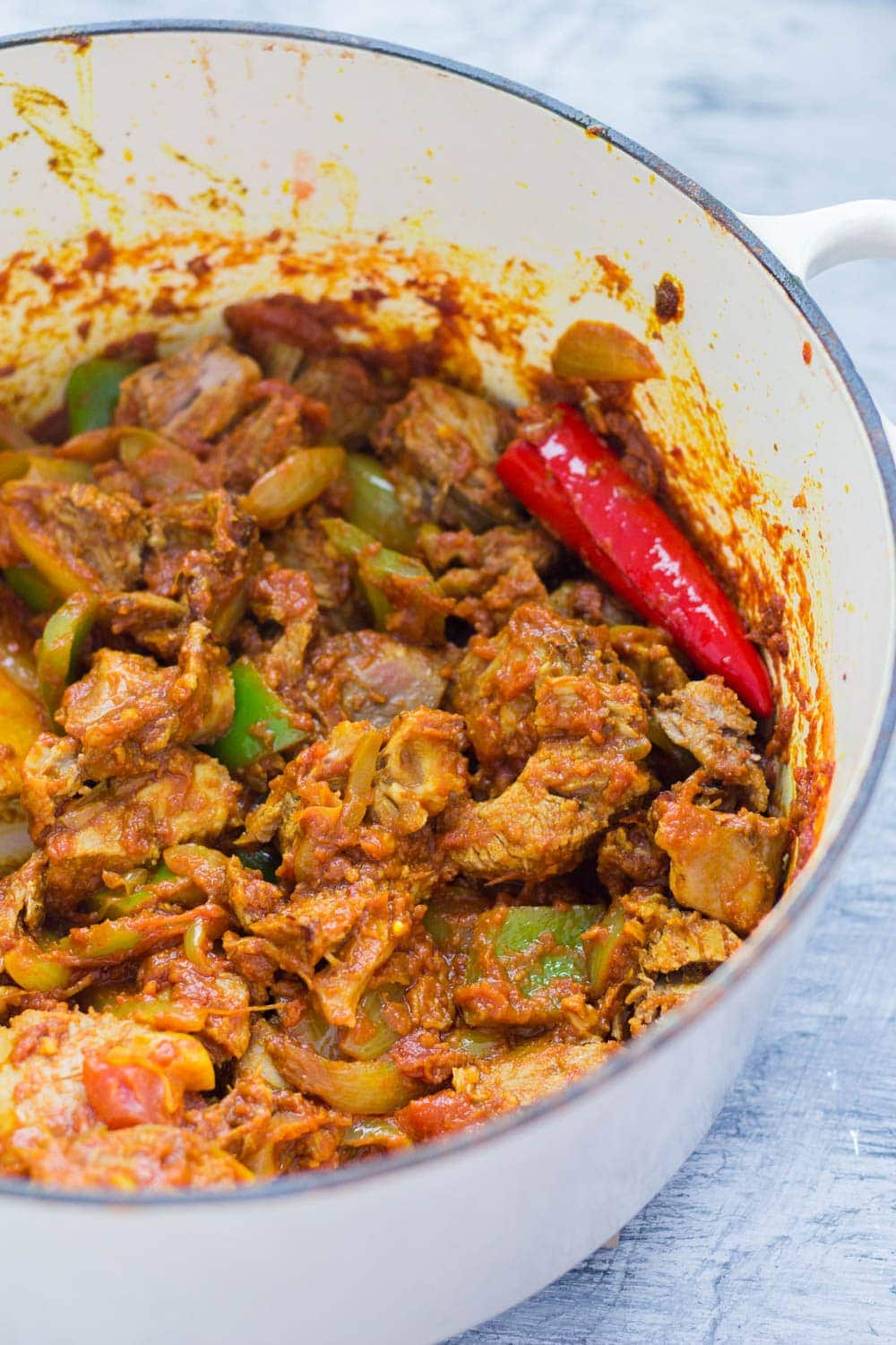 White pot with leftover turkey curry on a light blue background